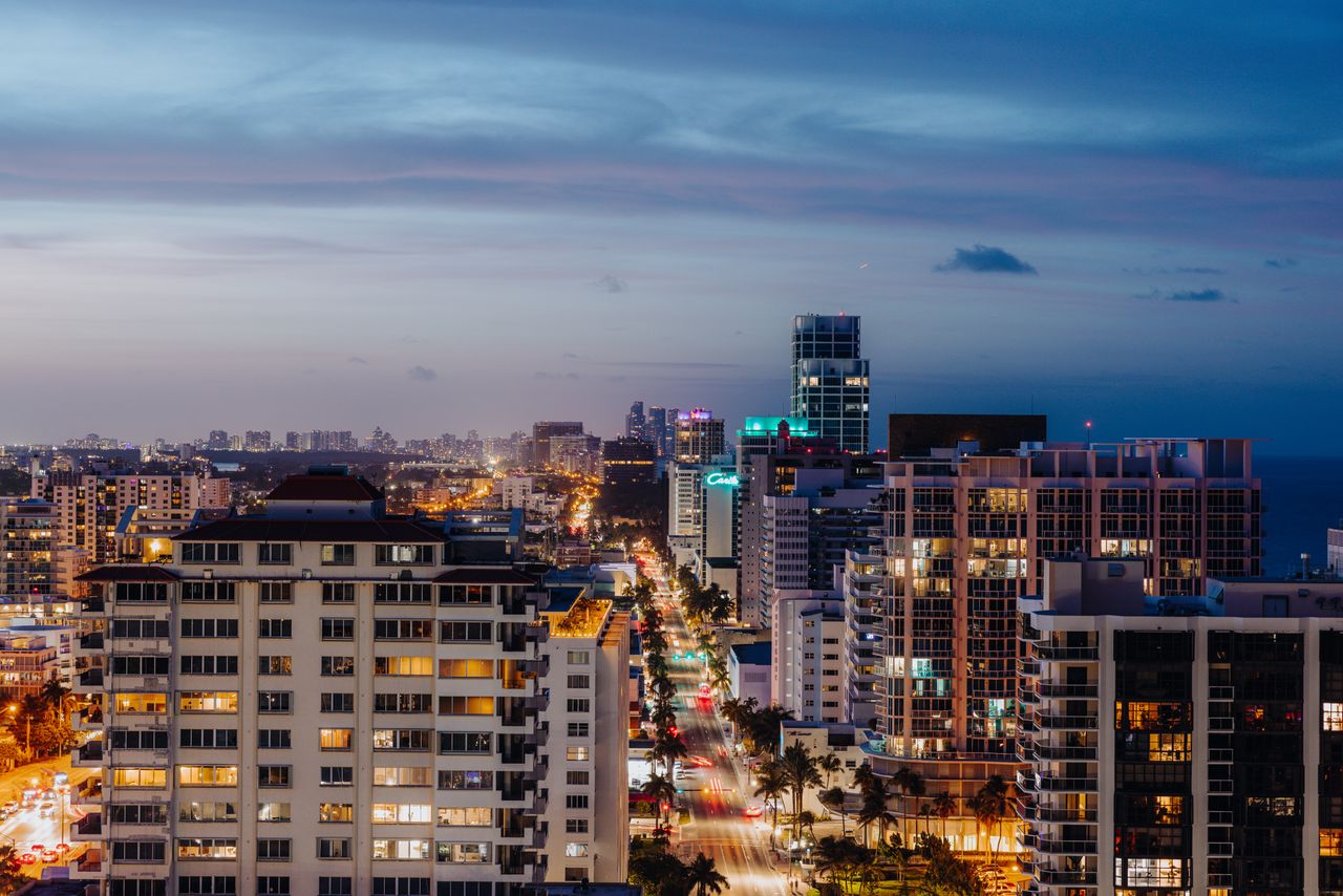 A stunning aerial view of a city's vibrant skyline at twilight, showcasing illuminated skyscrapers and bustling roads.