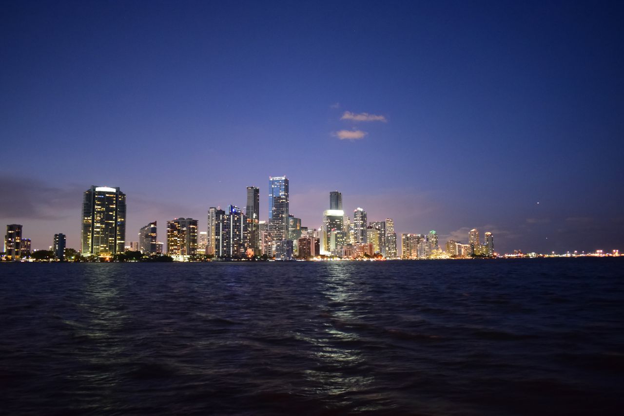 Contact Breathtaking view of Miami's skyline reflecting on Biscayne Bay at twilight.