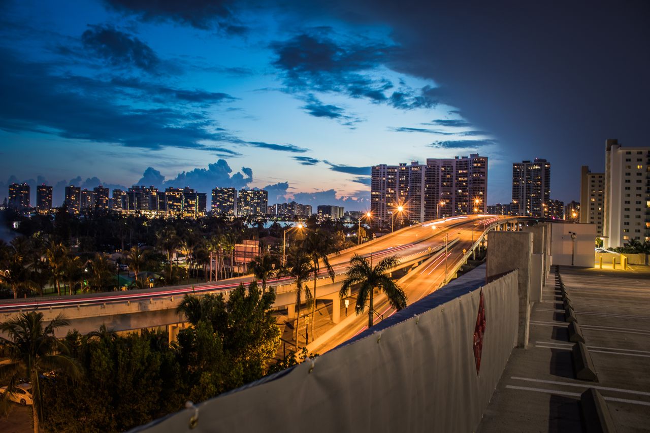A beautiful twilight view of Miami Beach skyline with palm trees and illuminated streets.
