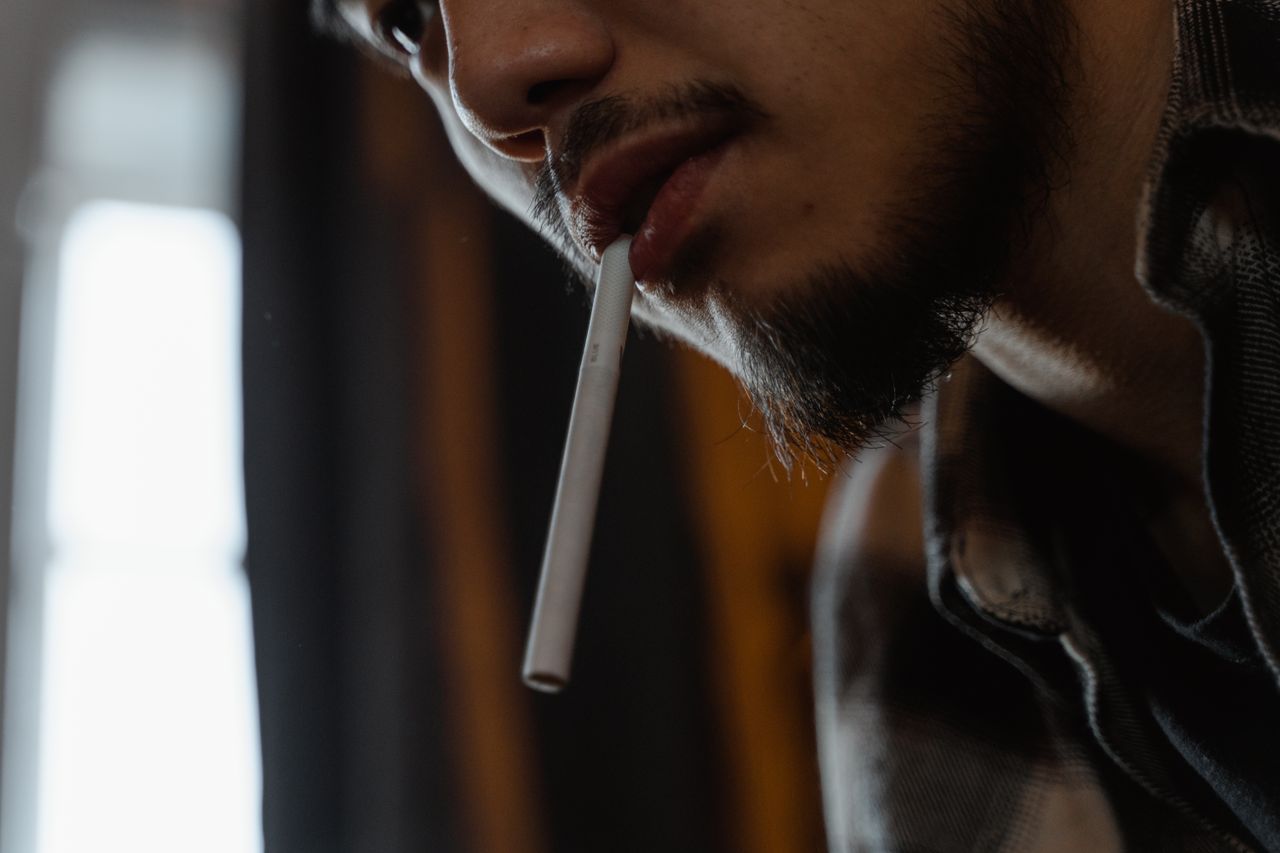 Close-up portrait of a man with a cigarette in his mouth, featuring a stylish beard.