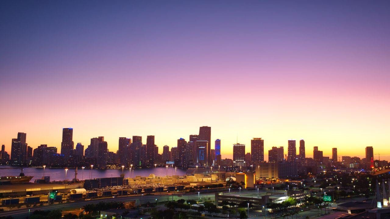 Aerial view of Miami's skyline at twilight with vibrant sunset colors casting a warm glow.